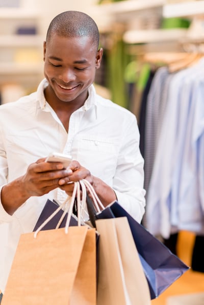 Shopping man texting on his phone at a store